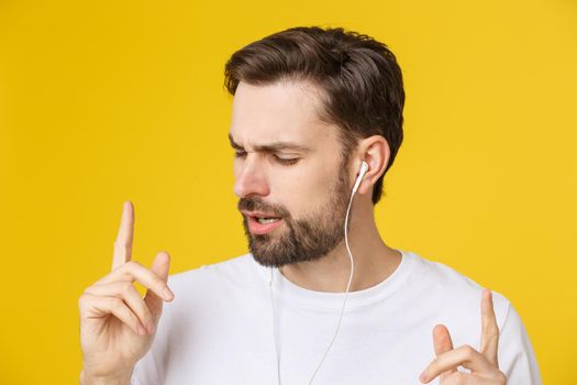 Handsome of a young man enjoying music over yellow background
