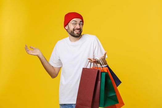 Bearded man with shopping bags with happy feeling isolated on yellow bacground.