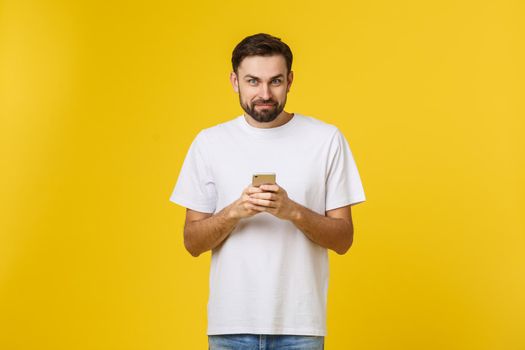 Portrait of a serious man talking on the phone isolated on a yellow background. Looking at camera.