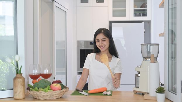 Cheerful asian standing at modern kitchen counter and preparing ingredient for making vegetarian food.