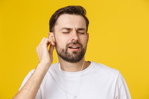 Handsome of a young man enjoying music over yellow background