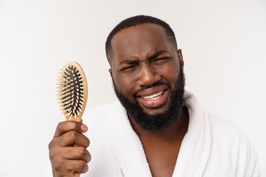 Portrait of handsome young african american man combing his hair in bathroom. Isolated over white background.