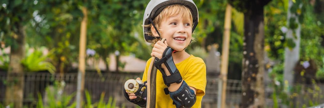 Athletic boy in helmet and knee pads learns to skateboard with in a skate park. Children education sports. BANNER, LONG FORMAT