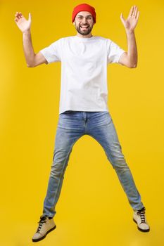 young casual man jumping for joy on yellow gold background.