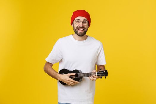 Young handsome guitar player. Studio shot on yellow background