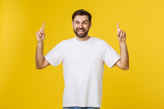 Man pointing showing copy space isolated on yellow background. Casual handsome Caucasian young man