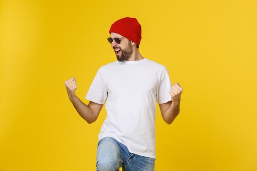 Successful young man celebrating against a yellow background