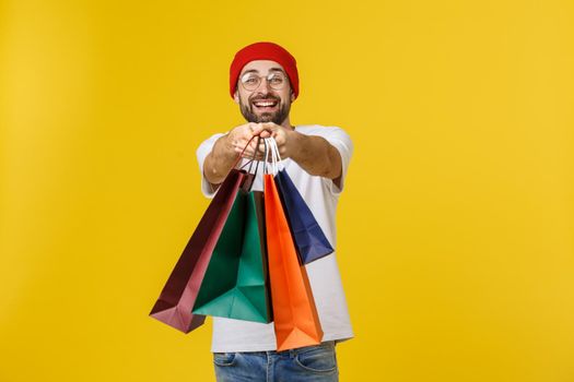 Bearded man with shopping bags with happy feeling isolated on yellow bacground.
