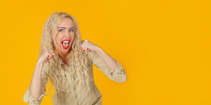 Cheerful, happy woman, raising her hands with her fist, cheering for the team, winning a huge bet, playing in the casino in delight, cheering friends, watching football, yellow background