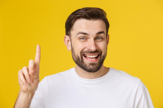 Thinking man isolated on yellow background. Closeup portrait of a casual young man finger up at copyspace. Caucasian male model