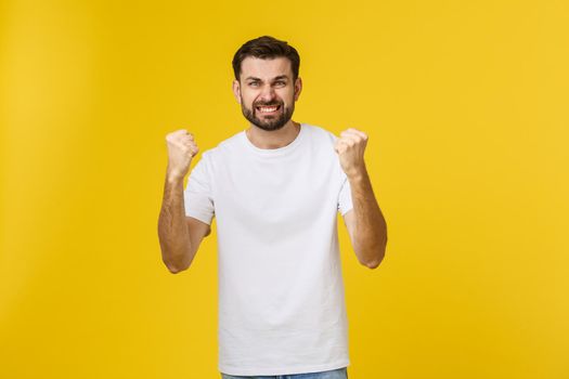 Happy young man with arms up isolated on a yellow background