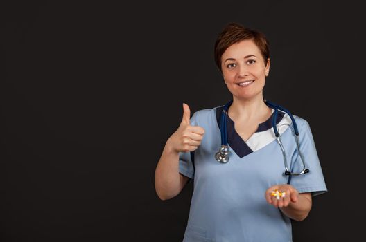 Young American doctor woman shows a background success sign making a positive gesture with hand, thumbs up smiling and happy. Looking at the camera with a cheerful expression, winner gesture.