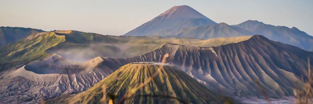 BANNER, LONG FORMAT Sunrise at the Bromo Tengger Semeru National Park on the Java Island, Indonesia. View on the Bromo or Gunung Bromo on Indonesian, Semeru and other volcanoes located inside of the Sea of Sand within the Tengger Caldera. One of the most famous volcanic objects in the world. Travel to Indonesia concept.