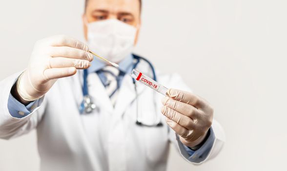 Test for coronavirus Covid-19. Male doctor or nurse doing nasal swab laboratory analysis in a hospital laboratory. A medical technologist holds a COVID-19 smear kit by wearing protective gloves.