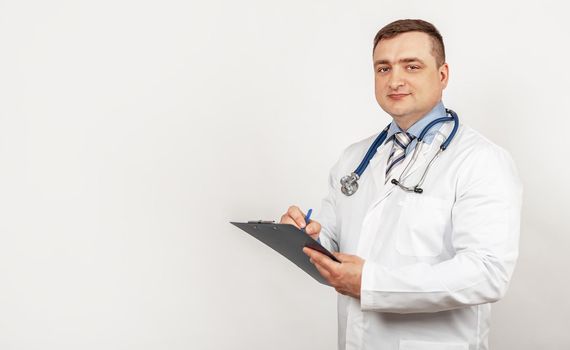 Men doctor writes with a pen a document on a tablet, writes a medical history. The concept of healthcare, medicine, and pharmacy.