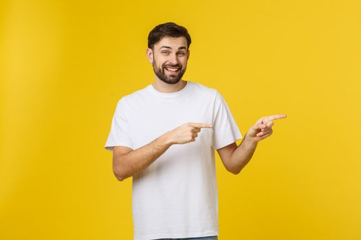 Man pointing showing copy space isolated on yellow background. Casual handsome Caucasian young man