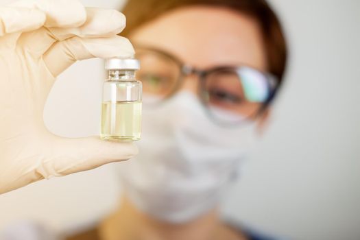 A doctor or nurse in nitrile gloves holds in his hand a vaccine vaccinated against influenza, measles, coronavirus COVID-19 for vaccination of children and adults, the concept of medicine and drugs.