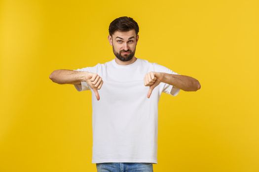 Young handsome man wearing white t-shirt over isolated background Doing thumbs down, disagreement and agreement expression. Crazy conflict