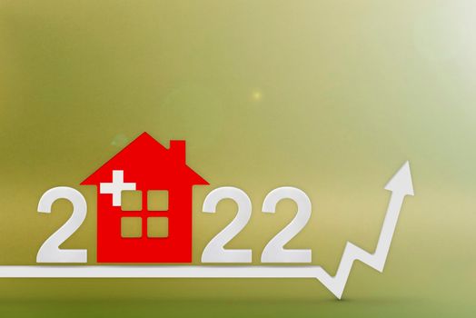 The cost of real estate in Switzerland in 2022. Rising cost of construction, insurance, rent in Switzerland. House model painted in flag colors, up arrow on yellow background.