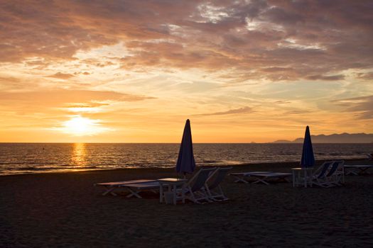 Two beach umbrellas closed at sunset in Forte dei Marmi beach