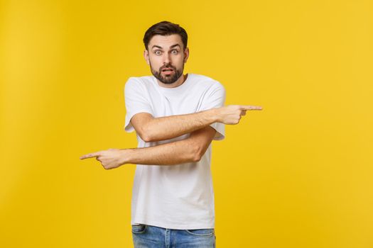 Handsome man over isolated yellow wall frustrated and pointing to the front