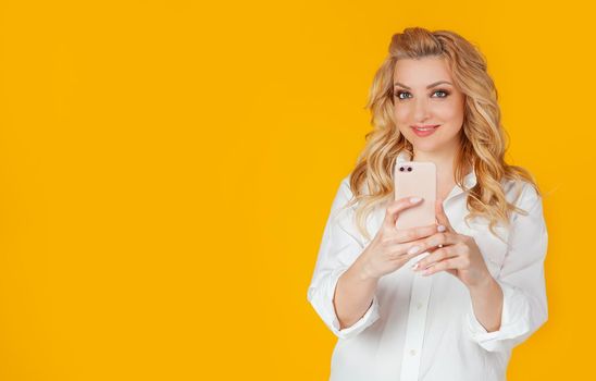Excited carefree european girl blogger takes photos of girlfriend using smartphone, holds camera, looks at camera, smiles, moment on social networks, blogger captures moment