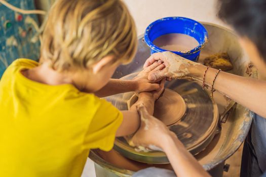 mother and son doing ceramic pot in pottery workshop. What to do with children. Child friendly place.
