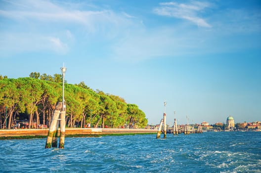 Parco delle Rimembranze park with green trees and embankment promenade of Venetian Lagoon in Venice city Castello sestiere, Lido island background, Veneto region, Northern Italy