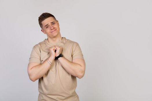 Handsome young man holding his palms pressed together, asking for forgiveness after a quarrel, looking at the camera. Language of the body
