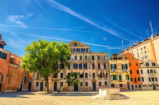 Palace buildings and stone well on Campo San Polo square in Venice historical city centre, blue sky background in summer day, Veneto Region, Northern Italy