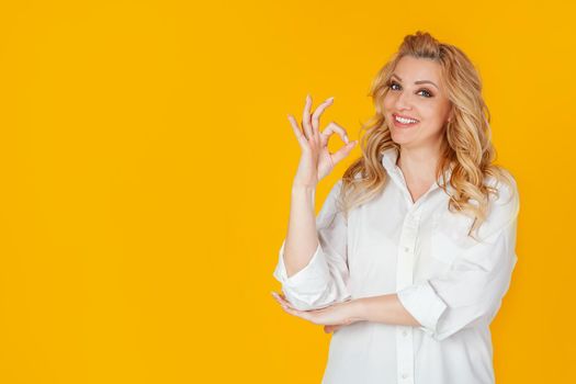 Charismatic self-confident cheerful, gorgeous adult woman, dressed in a white shirt, smiling broadly, showing a good gesture, excellent mood, guaranteeing everything amazing