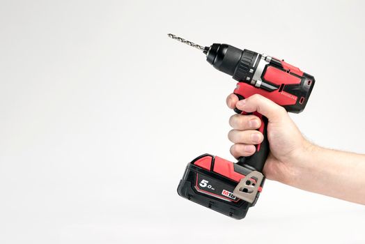 Cordless drill in black and red. Screwdriver with a drill in hand on a white background. Modern carpentry tool