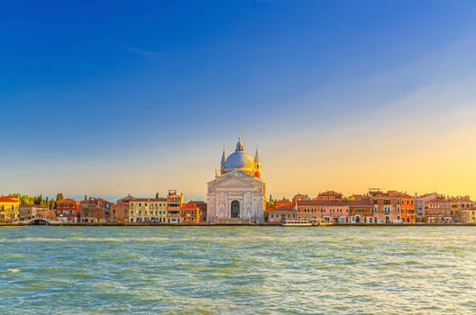 Chiesa del Santissimo Redentore catholic church and row of buildings on fondamenta embankment of Giudecca island canal in Venetian Lagoon, sunset view from Venice city, Veneto region, Northern Italy