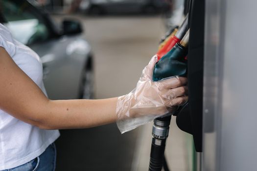 Close-up of a women's hand using a fuel nozzle at a gas station. Petrol station concept. Filling station at petrol gasoline.