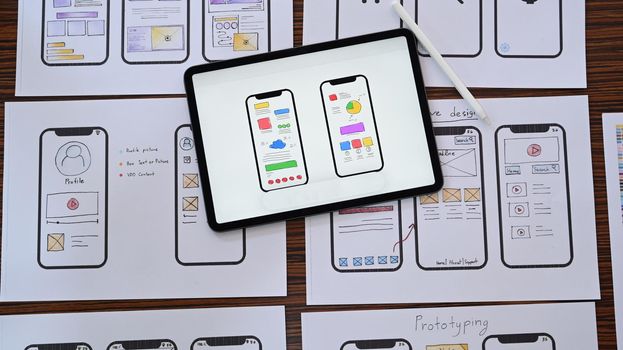 Web developer workplace with sketches of mobile application on wooden table. Flat lay, Top view.