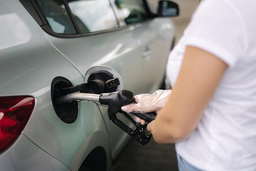 Woman is refueling at gas station. Female hand filling benzine gasoline fuel in car using a fuel nozzle. Petrol prices concept. Close-up of hand.