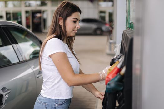 Woman is preparing for refueling at gas station. Female hand filling benzine gasoline fuel in car. Petrol prices concept. Self-service.