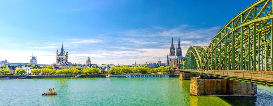 Panorama of Cologne city historical centre with Cologne Cathedral of Saint Peter, Great Saint Martin Roman Catholic Church buildings and Hohenzollern Bridge across Rhine river. Cologne panoramic view