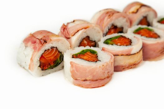 Sushi roll with bacon and salmon on a white background, ingredients seared bacon, salmon, green onions, flying fish roe, Iceberg sauce, rice, nori. Traditional Japanese food. For the restaurant menu
