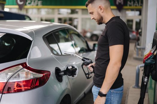 Man is refueling at gas station. Male hand filling benzine gasoline fuel in car using a fuel nozzle. Petrol concept.