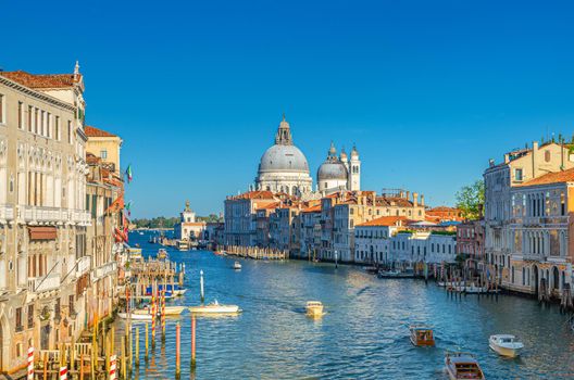 Venice cityscape with Grand Canal waterway. Gondolas and boats docked and sailing Canal Grande. Santa Maria della Salute Roman Catholic church on Punta della Dogana. Veneto Region, Italy.