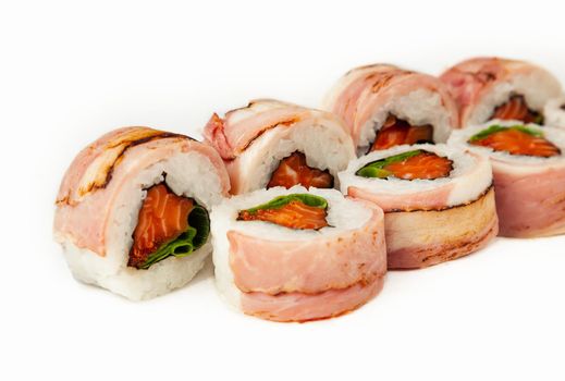 Sushi roll with bacon and salmon on a white background, ingredients seared bacon, salmon, green onions, flying fish roe, Iceberg sauce, rice, nori. Traditional Japanese food. For the restaurant menu