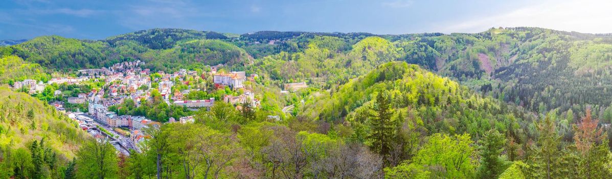 Karlovy Vary city aerial panoramic view with row of colorful multicolored buildings and spa hotels in historical city centre. Panorama of Karlsbad town and Slavkov Forest mountains, Czech Republic