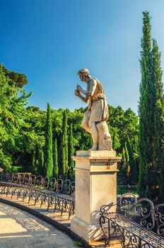 Androne monument statue and metal iron benches in Villa Bellini park in Catania historical city centre of Sicily island, clear blue sky background, southern Italy