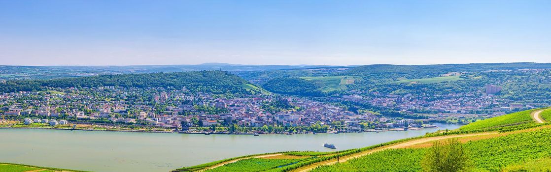 Aerial panoramic view of river Rhine Gorge or Upper Middle Rhine Valley winemaking region with vineyards green fields, Bingen am Rhein town, blue sky, Rhineland-Palatinate, Hesse states, Germany