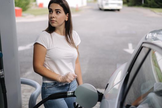 Woman is refueling at gas station. Female hand filling benzine gasoline fuel in car. Petrol prices concept.