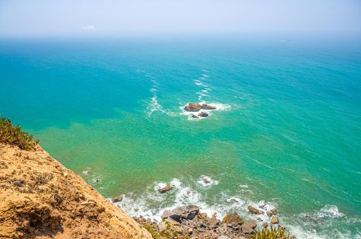 Cabo da Roca or westernmost point of continental Europe and Eurasia, view of Atlantic Ocean turquoise water and endless horizon from Cape Roca rocks and cliffs, Sintra municipality, Portugal