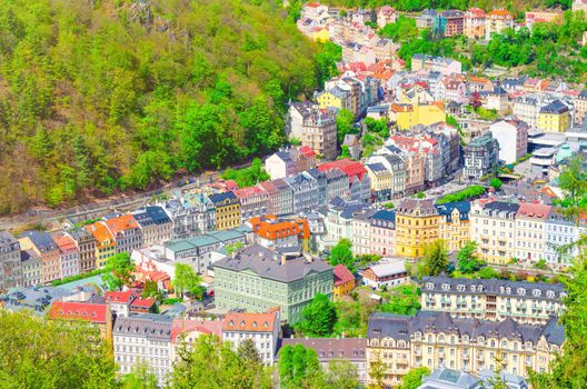 Karlovy Vary Carlsbad historical city centre top aerial view with colorful beautiful buildings, Slavkov Forest hills with green trees on slope, close-up, West Bohemia, Czech Republic