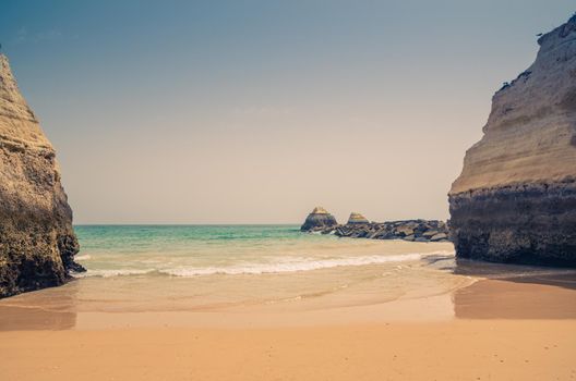 Landscape of beautiful sandy beach Praia dos Tres Castelos with rocks and cliffs in Portimao town, Algarve district, turquoise water of Atlantic Ocean in sunny day, blue sky background, Portugal