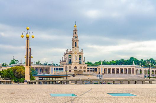 Sanctuary of Our Lady of Fatima with Basilica of Our Lady of the Rosary catholic church with colonnade and street lantern lamp in Fatima town historical centre, Portugal